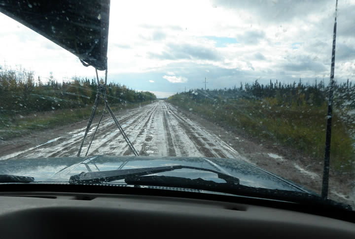 Vehicle Driving Down a Poor Quality Wet Gravel Road, a Tough Road to Follow
